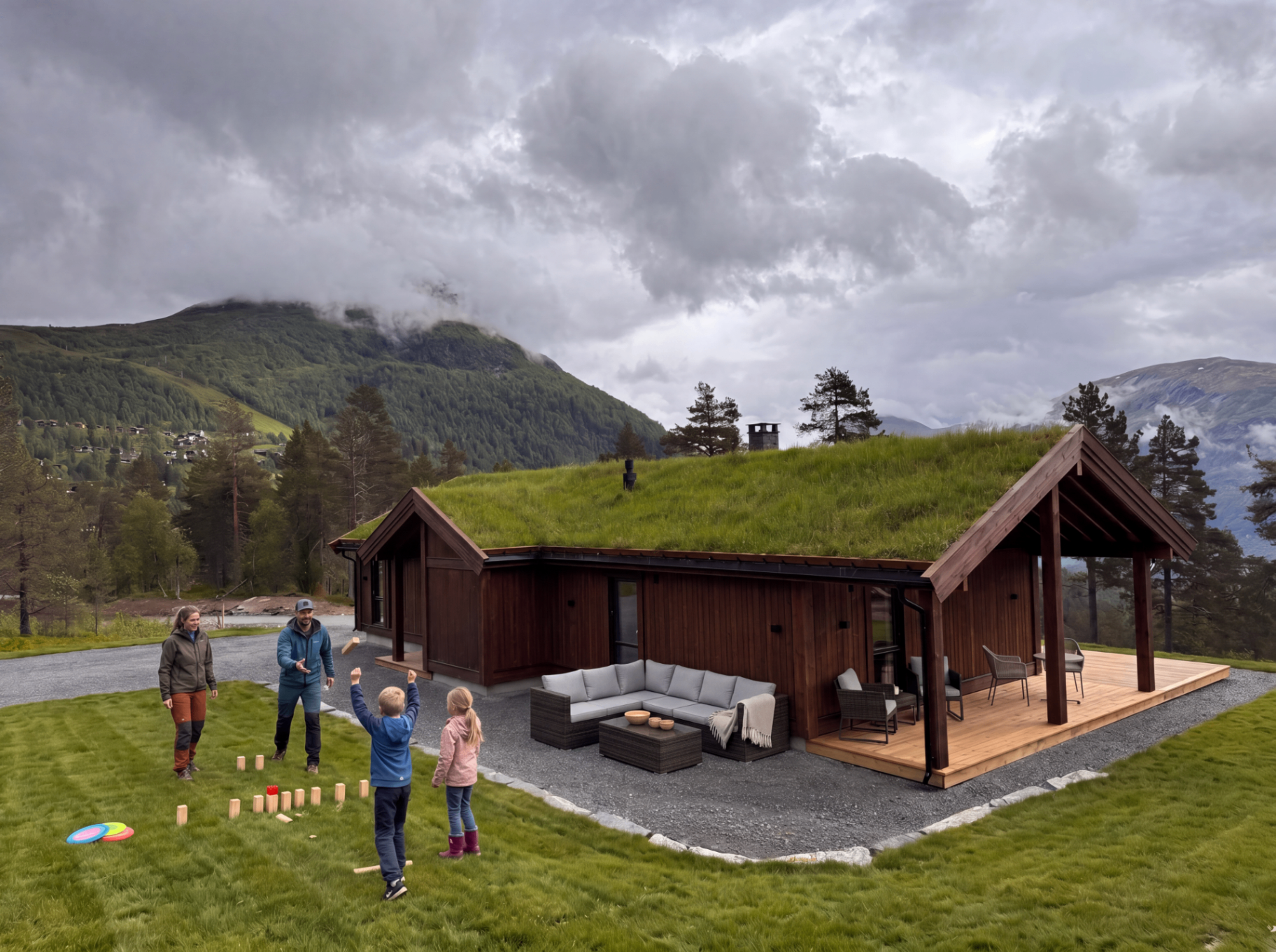 Hytte med torvtak og overbygd terrasse i frodig fjellandskap